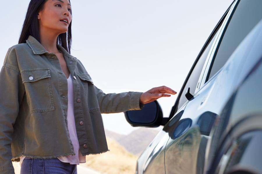 Ford Mustang Mach-E grigia. Una donna apre la porta del conducente